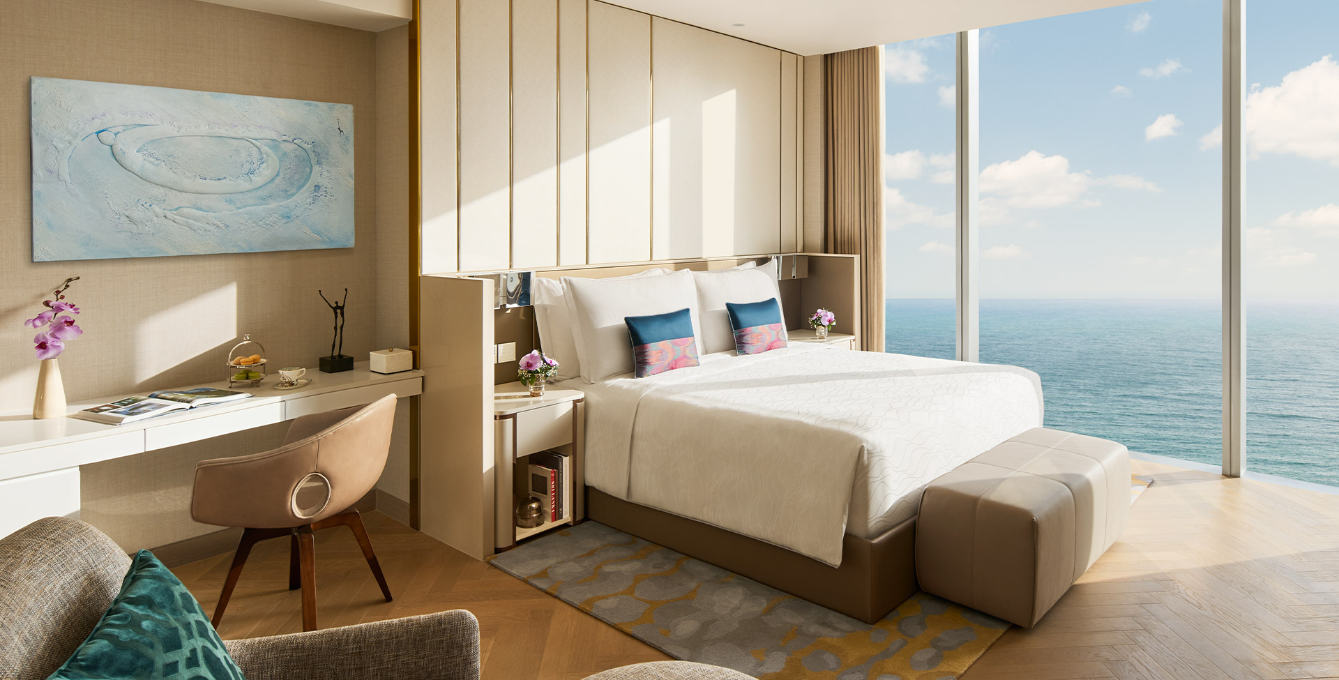 A Premium Suite bedroom in pale timber and cream, the ocean beyond the window